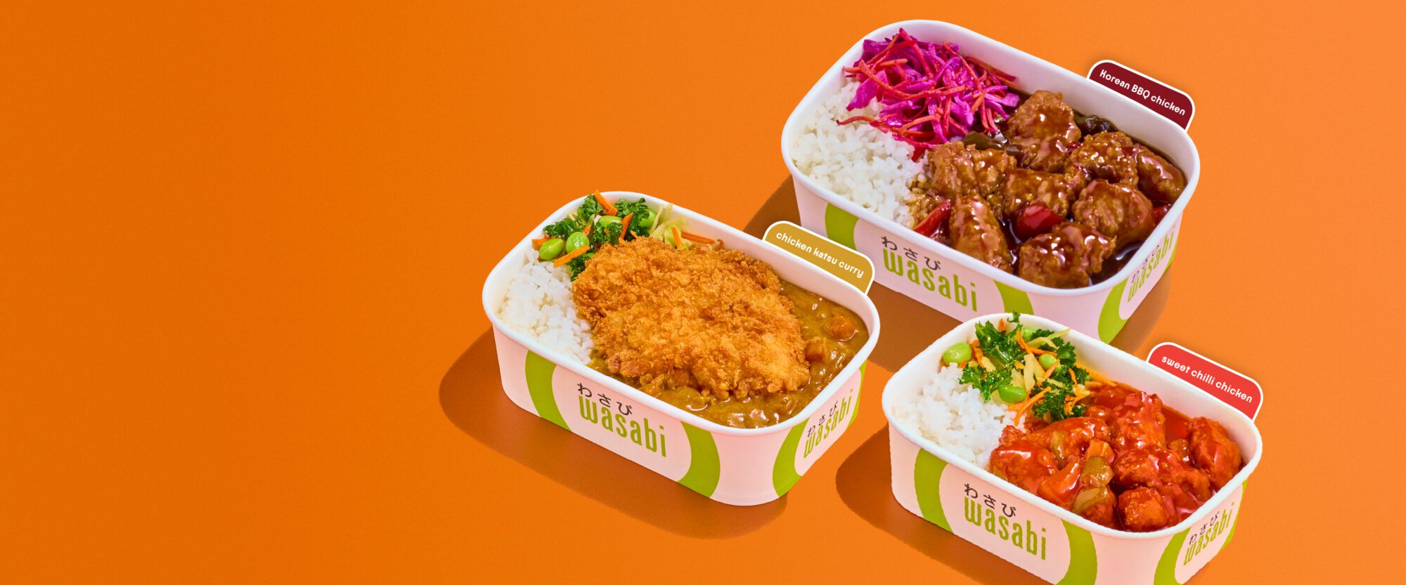 Three Wasabi-branded takeaway containers with rice dishes: breaded cutlet with curry, beef with red cabbage, and a spicy chicken dish, all on an orange background.